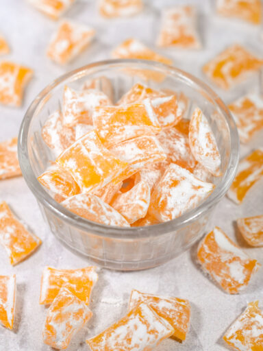A bowl of homemade lemon drops hard candy on a white surface