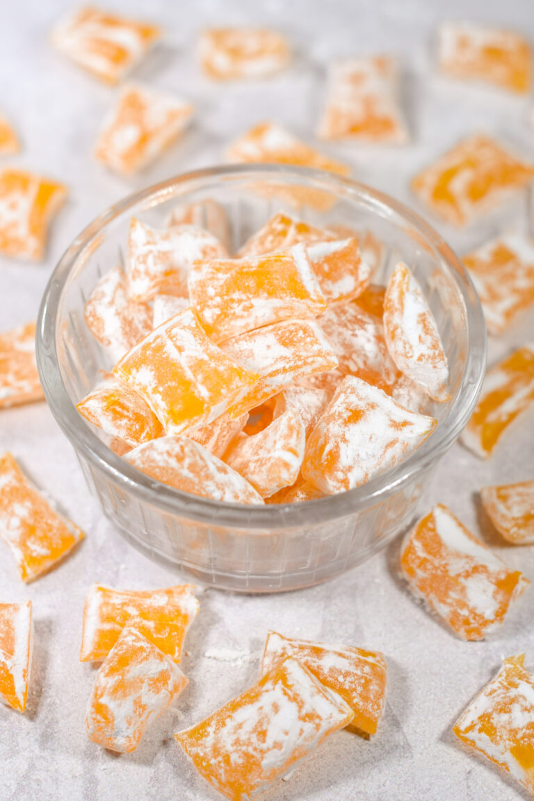 A bowl of homemade lemon drops hard candy on a white surface