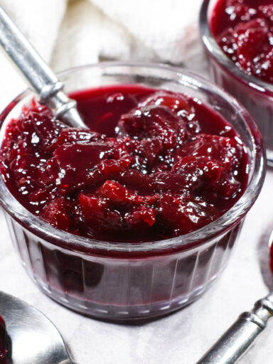 A small glass dish of cherry compote, with a metal spoon