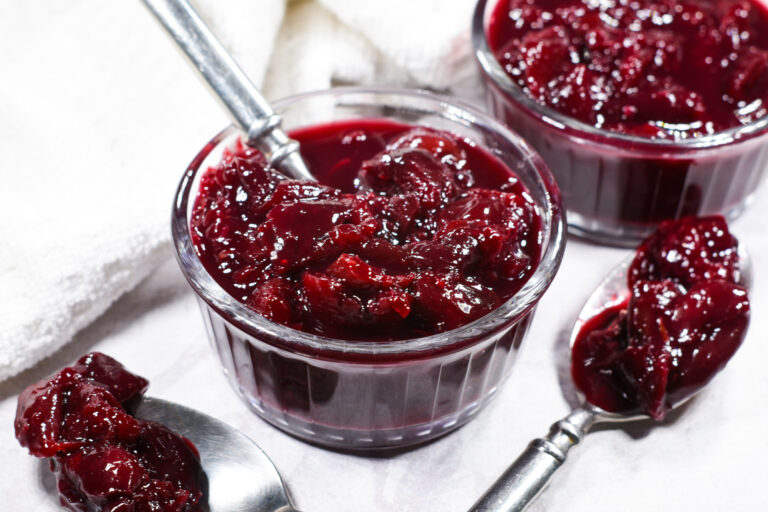 A small glass dish of cherry compote, with a metal spoon