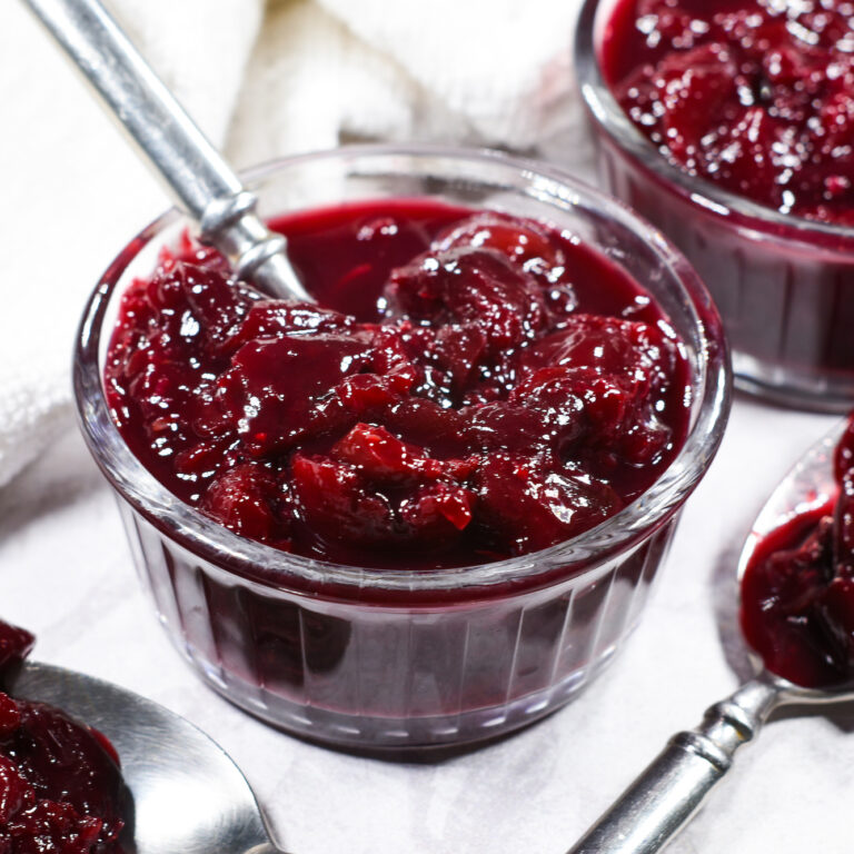 A small glass dish of cherry compote, with a metal spoon