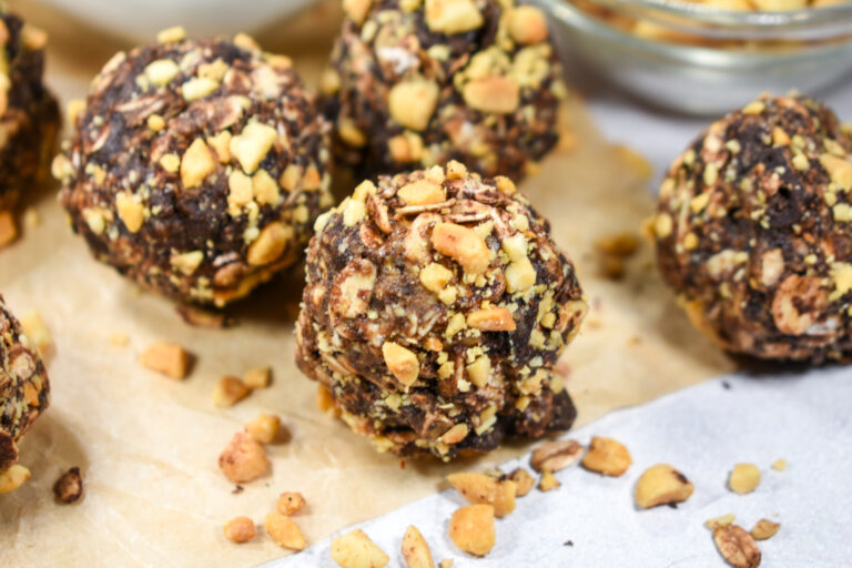 Chocolate oatmeal bites rolled in peanuts, on a sheet of baking parchment