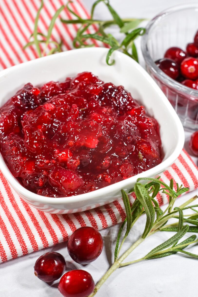 Homemade cranberry sauce in a white bowl, sitting on a striped towel