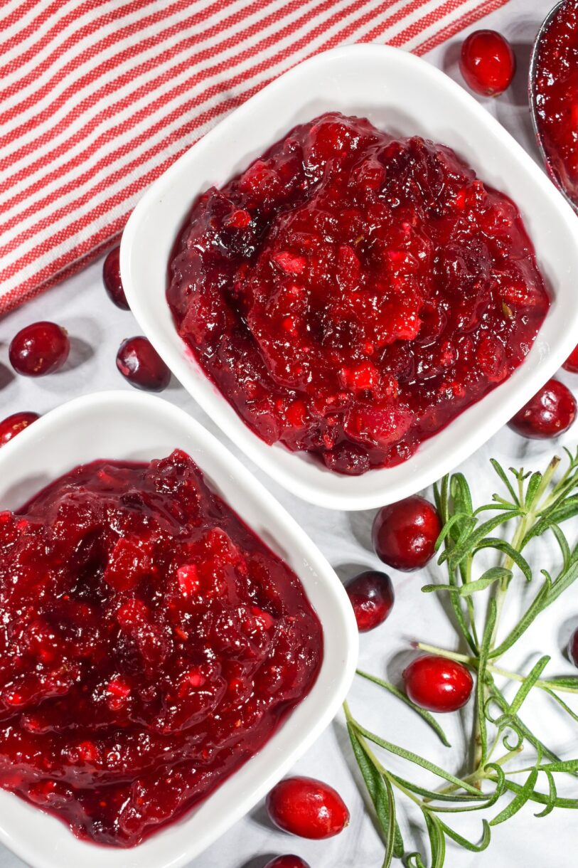 Two dishes of bright red cranberry compote and fresh cranberries