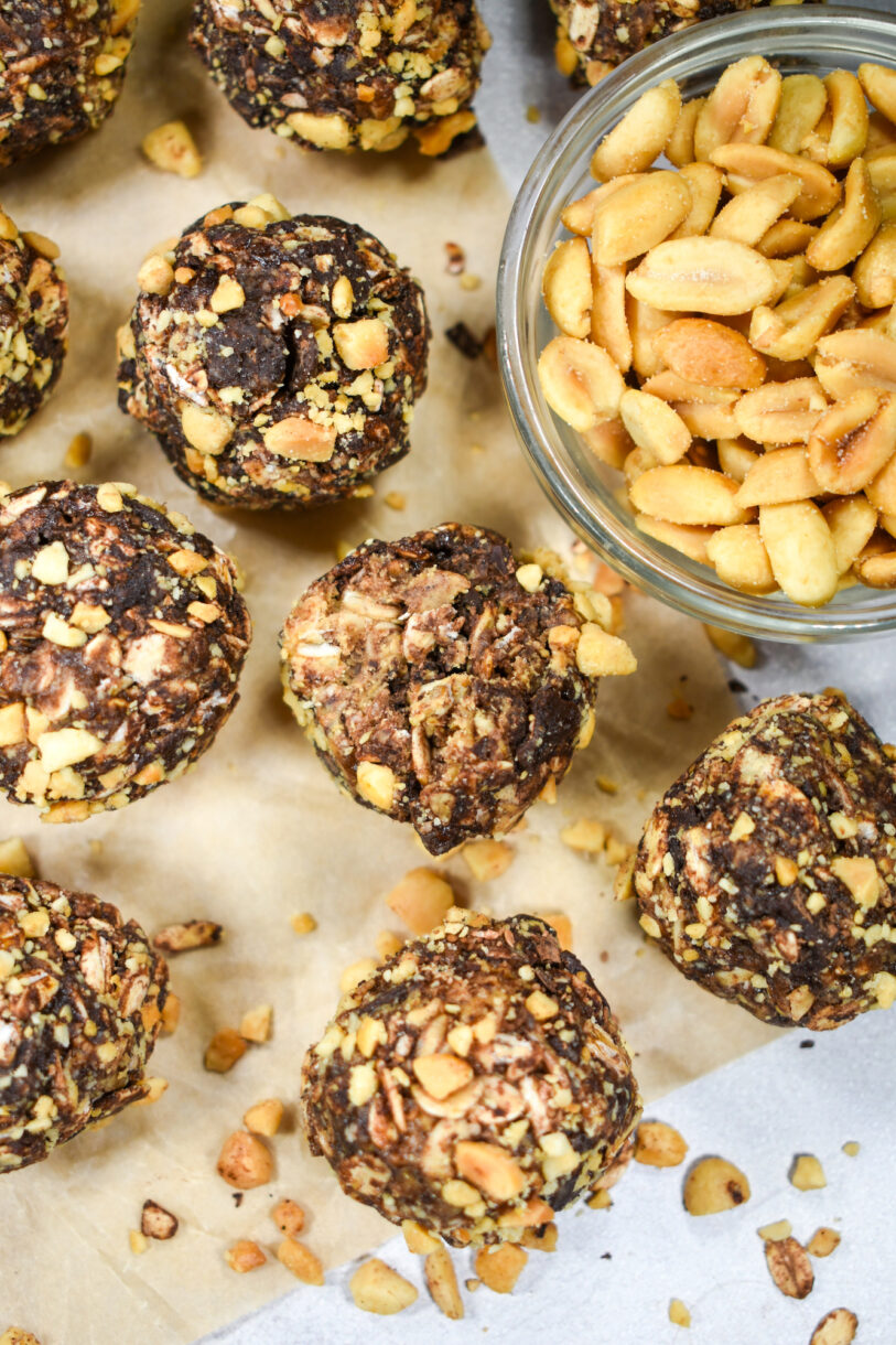 Chocolate oatmeal balls rolled in peanuts, on a sheet of baking parchment