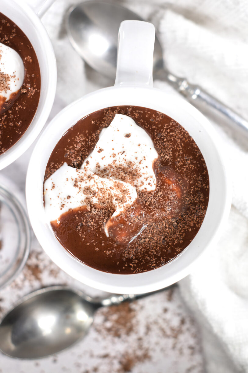 Looking down into a mug of dairy free cocoa topped with coconut whipped cream