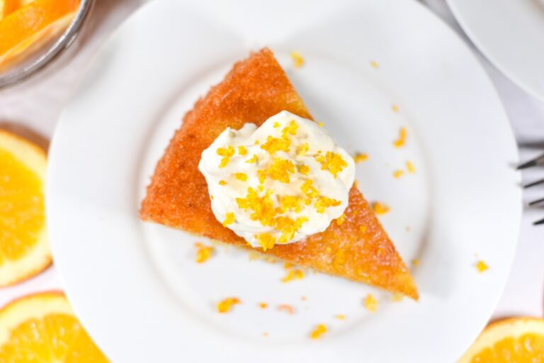 a slice of orange almond cake with whipped cream and orange zest
