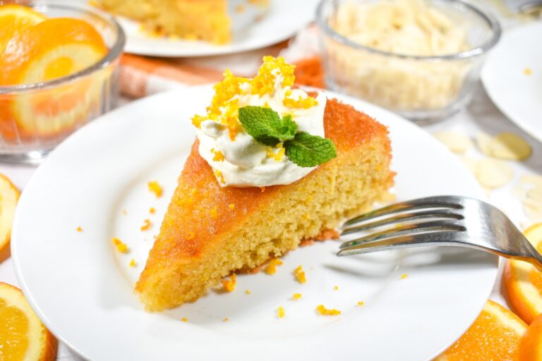 Flour less orange cake slice on a plate with a fork