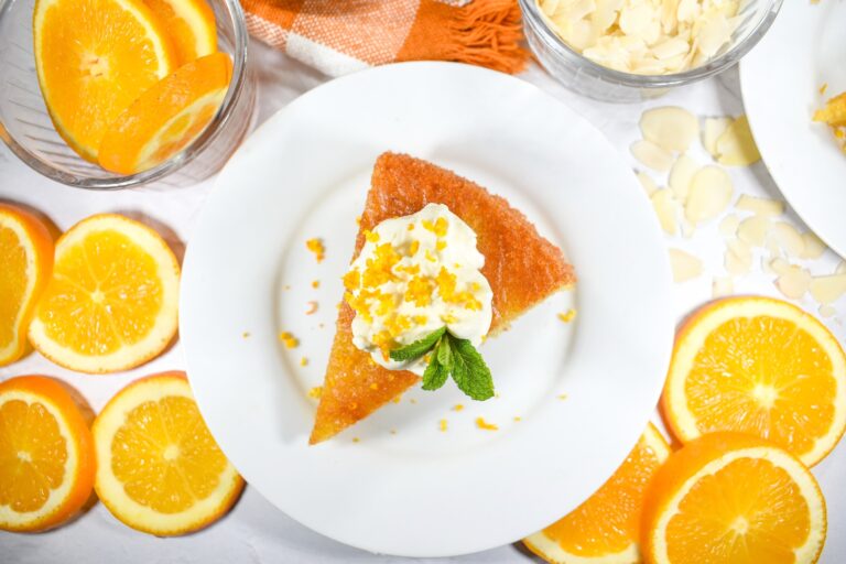 Flourless orange and almond cake on a plate surrounded by oranges