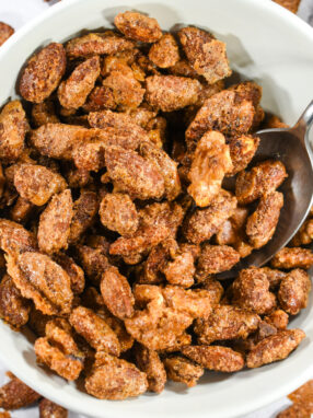 A bowl of spiced nuts on a white surface