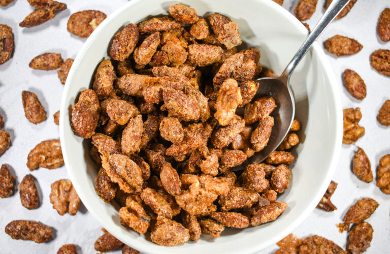 A bowl of spiced nuts on a white surface