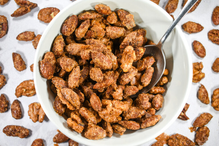 A bowl of spiced nuts on a white surface