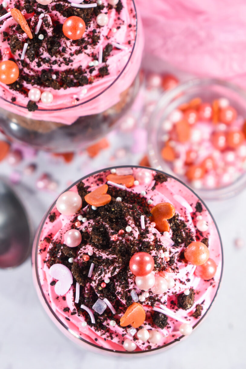 A pink Valentine's Day parfait topped with crushed oreos and sprinkles