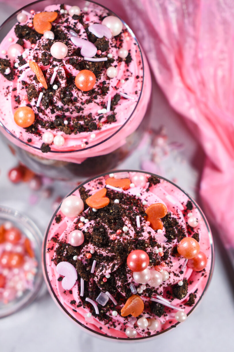 A pink Valentine's Day dessert parfait topped with crushed oreos and sprinkles