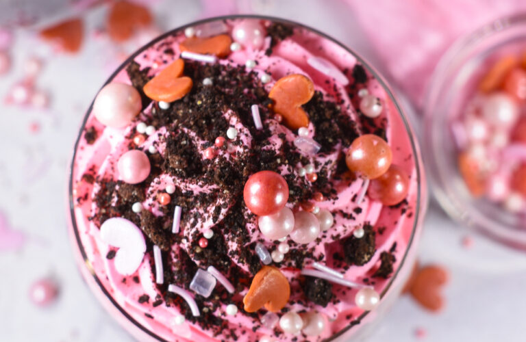 Looking down at a parfait with pink whipped cream, crushed oreos and sprinkles