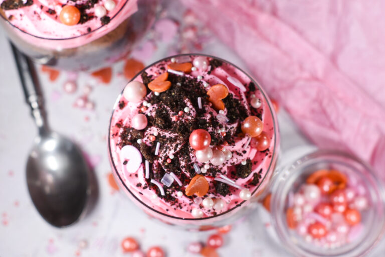 A pink Valentine's Day parfait topped with crushed oreos and sprinkles
