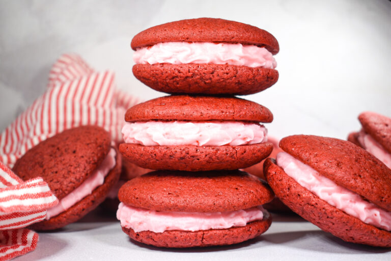 A stack of red velvet whoopie pies with pink frosting