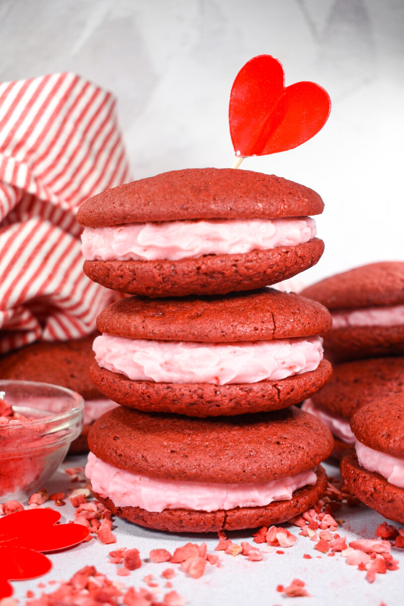 A stack of red velvet whoopie pies with pink frosting