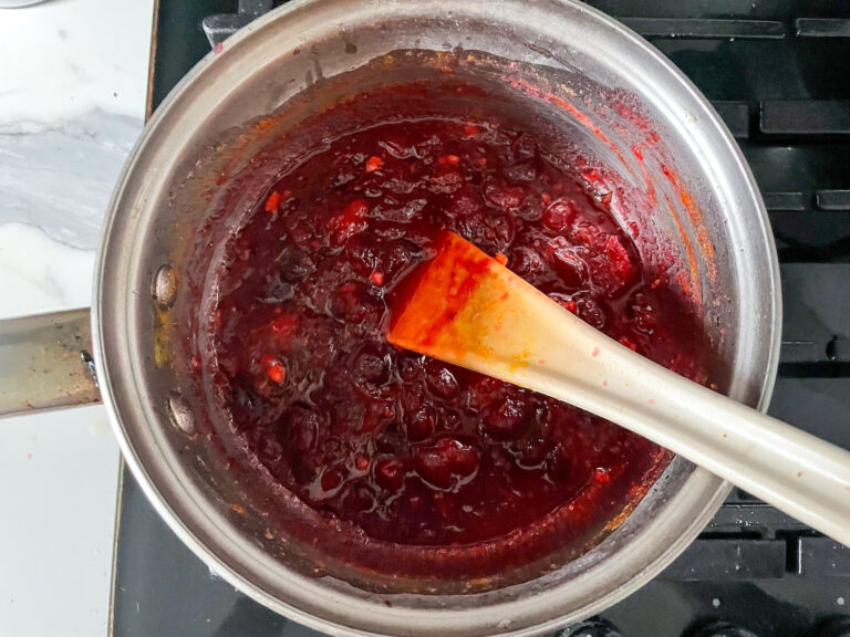 Cranberry sauce cooking on stovetop with spoon