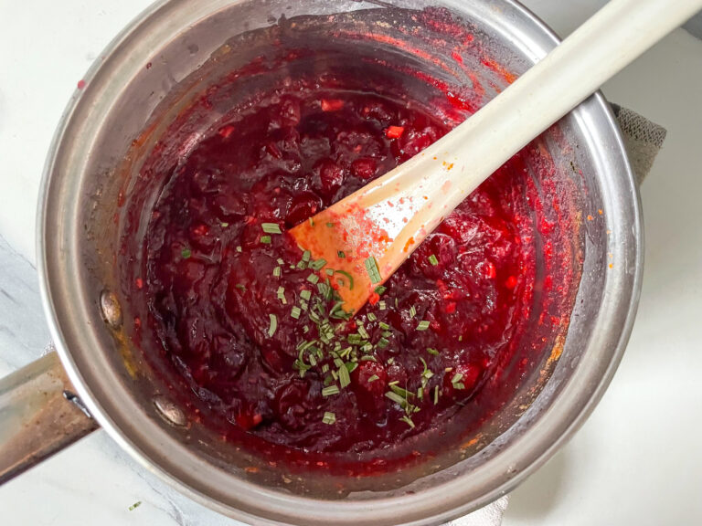 Stirring in chopped rosemary to cooked cranberry sauce