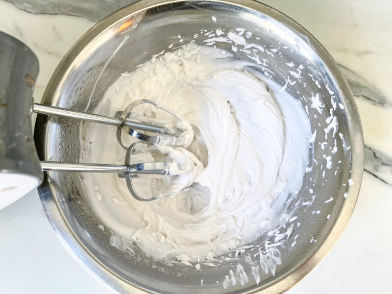 A bowl of coconut whipped cream and a mixer