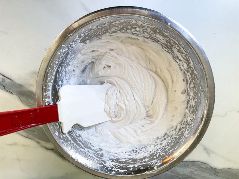 A bowl of coconut whipped cream and a spatula