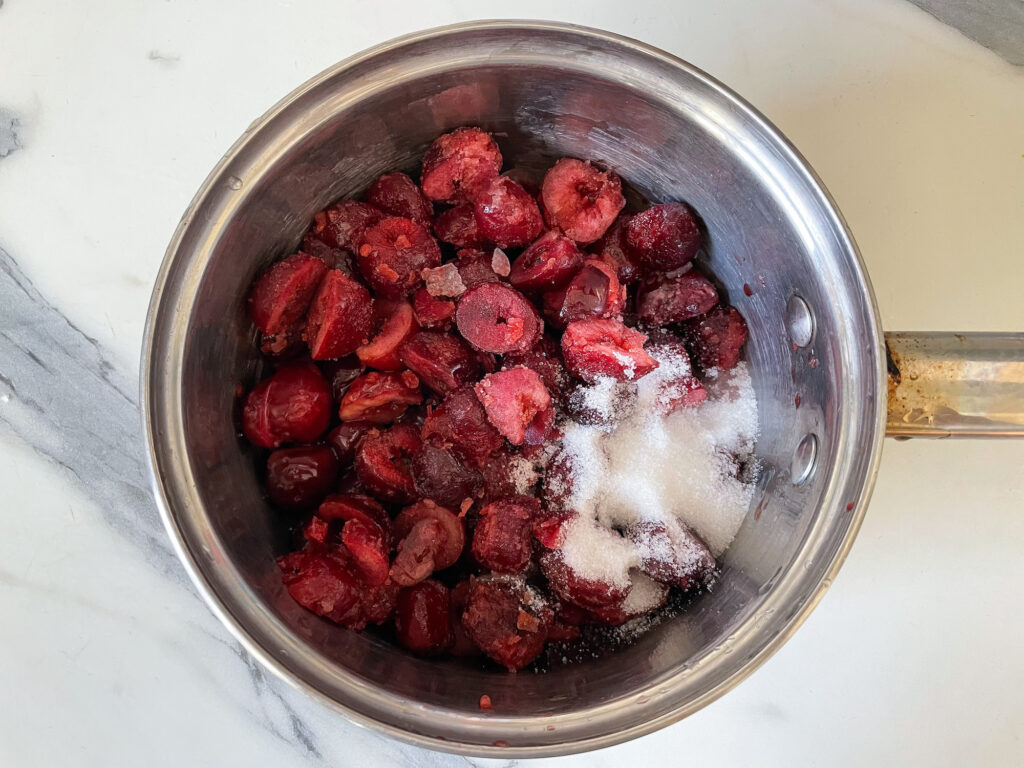 A saucepan with cherries and sugar