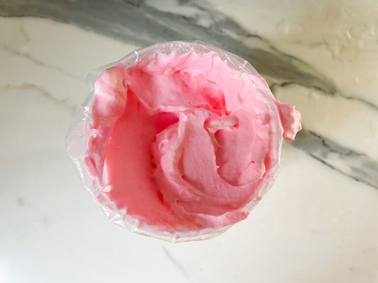 Pink whipped cream in a piping bag