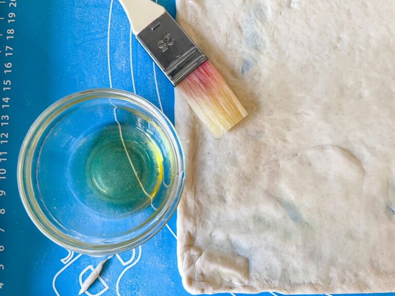 Homemade pizza dough, dish of oil, and pastry brush