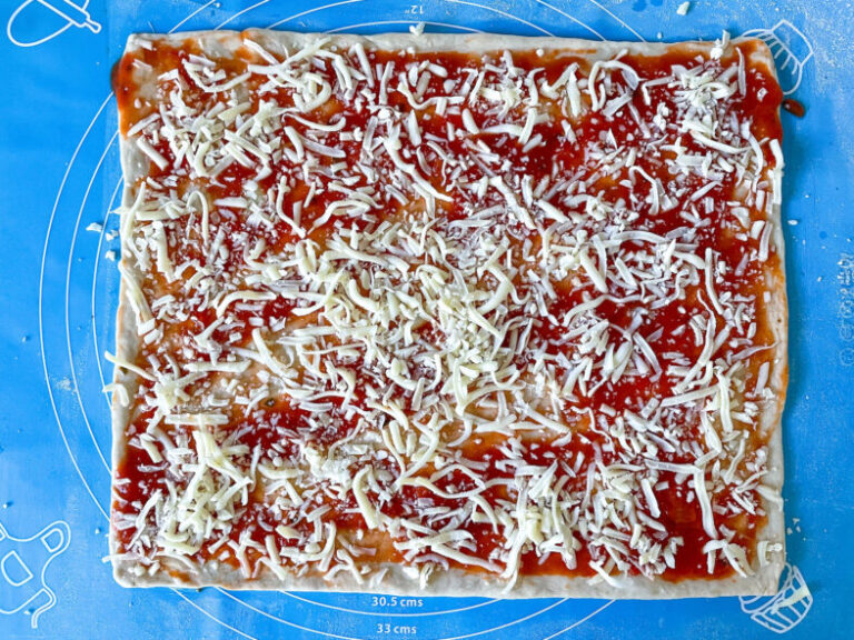 Homemade pizza dough scattered with shredded cheese