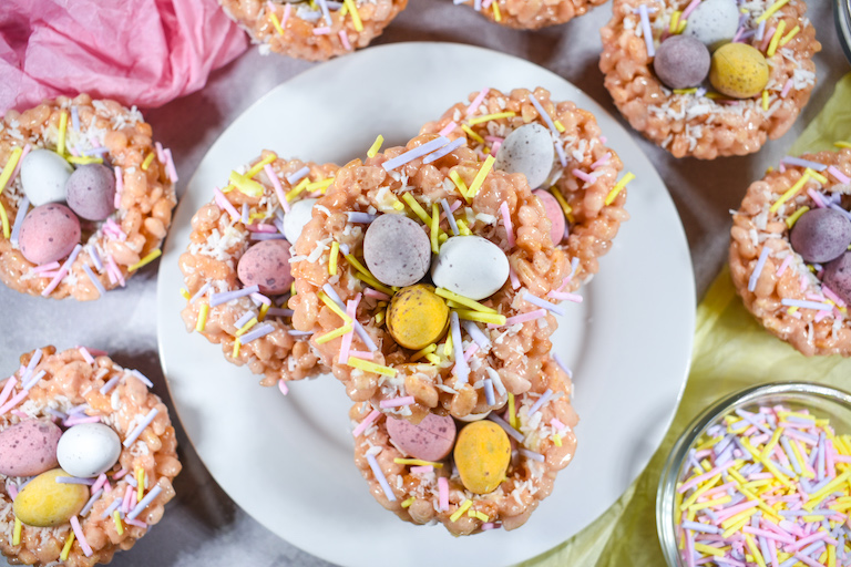A white plate with a stack of rice krispie bird nest treats decorated with mini eggs