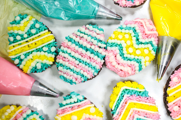 Egg shaped Easter brownies and pink, blue, and yellow frosting in piping bags