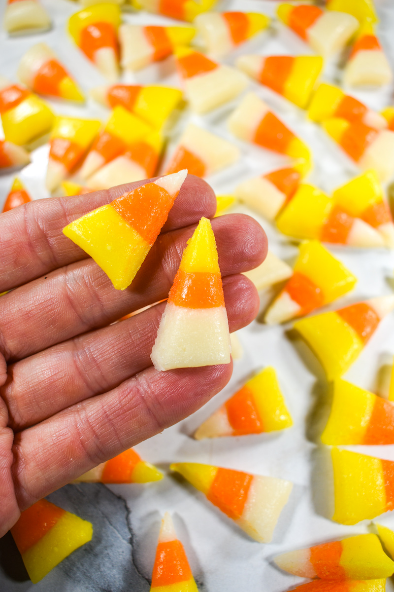 Hand holding two pieces of homemade Halloween candy corn