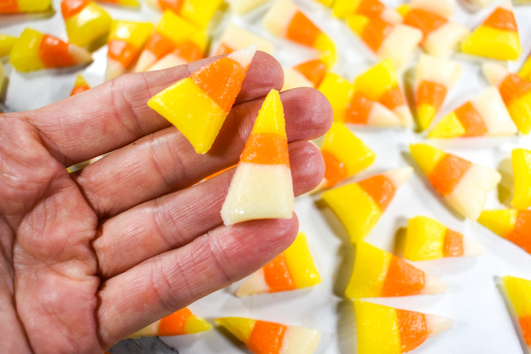 Hand holding two pieces of homemade candy corn