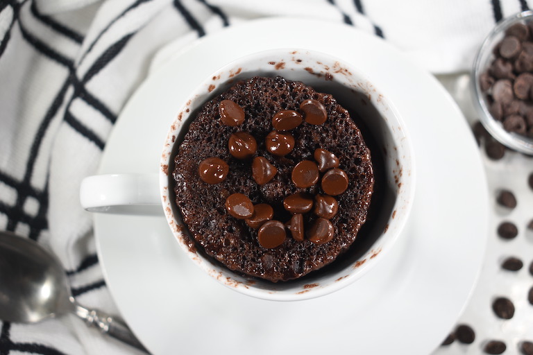 Chocolate mug cake in a white mug, with half melted chocolate chips on top