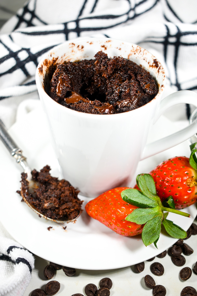 Chocolate mug cake with a spoon, strawberries, and chocolate chips