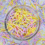 A glass dish of yellow, pink, and purple homemade sprinkles