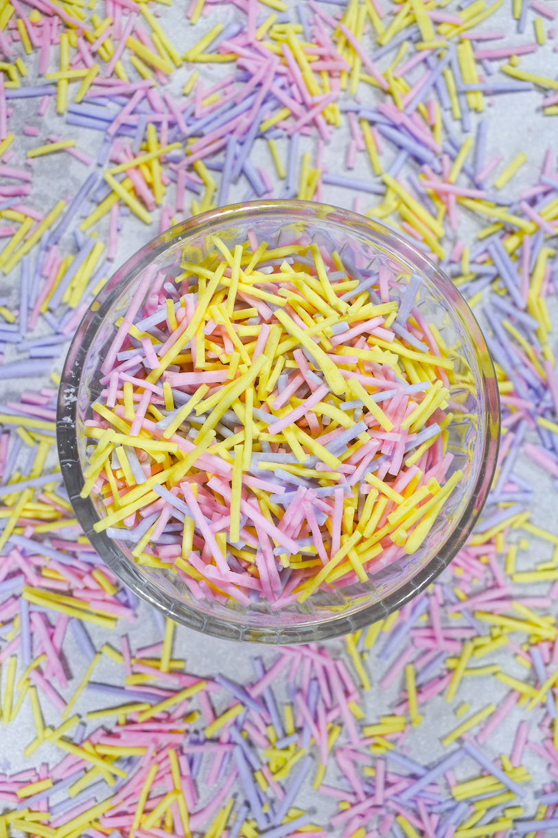 A bowl of pink, yellow, and purple homemade sprinkles