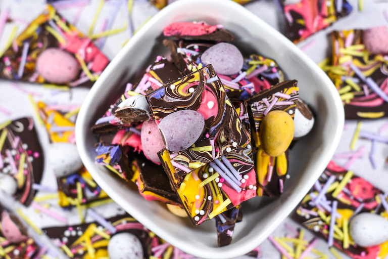 Chocolate bark made from an Easter bark recipe with mini eggs, in a bowl on a white surface