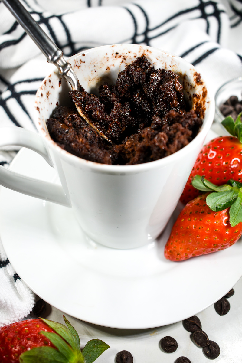 Microwave mug cake on a plate with red strawberries