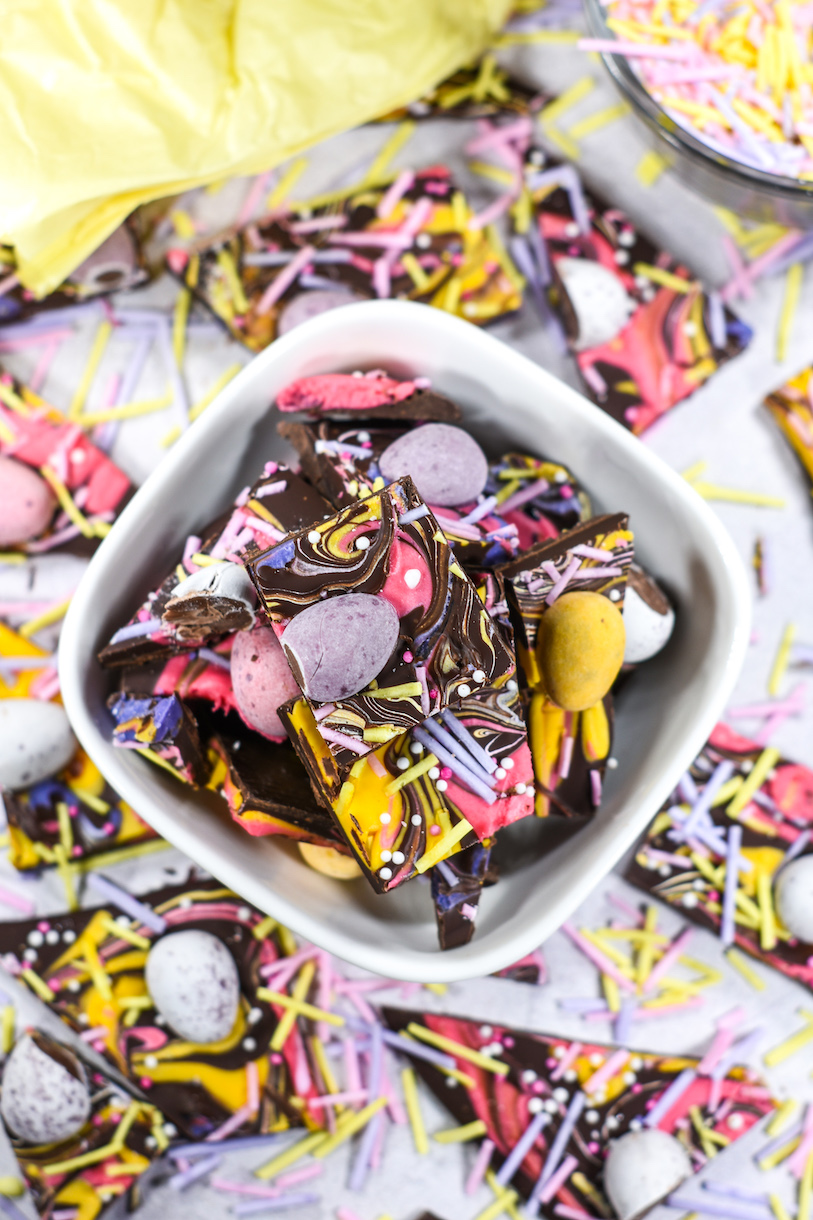Closeup of a bowl of mini egg Easter bark on a white surface with sprinkles