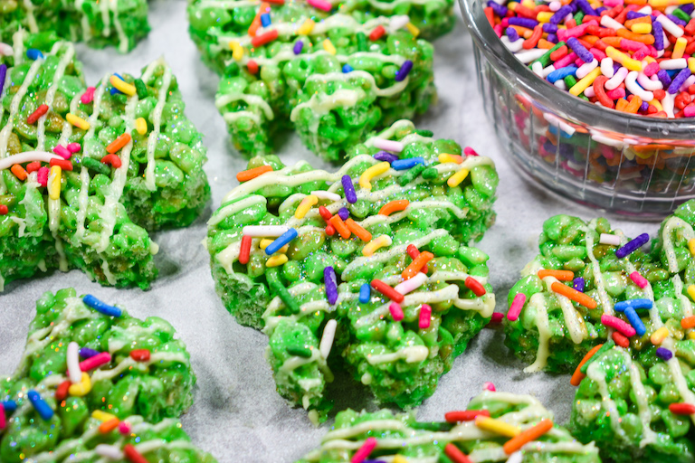 Green rice krispie treats shaped like shamrocks, decorated with rainbow sprinkles