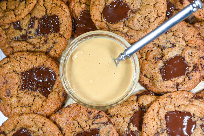 Looking down into a bowl of tahini, surrounded by chocolate chunk cookies