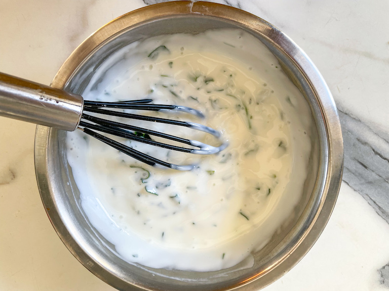 A whisk in a bowl of yogurt dip for veggies