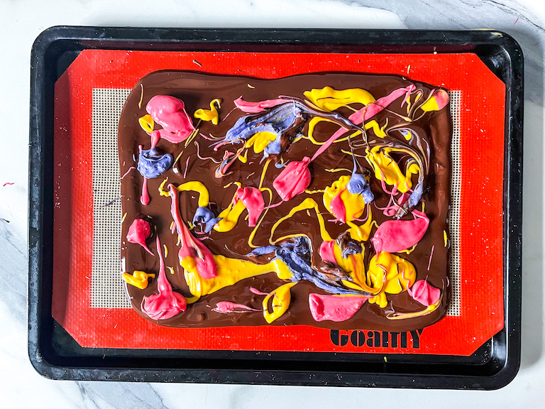 Melted chocolate with swirls of pink, yellow, and purple