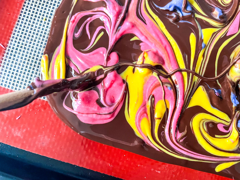 Swirling pink and yellow chocolate with a chopstick