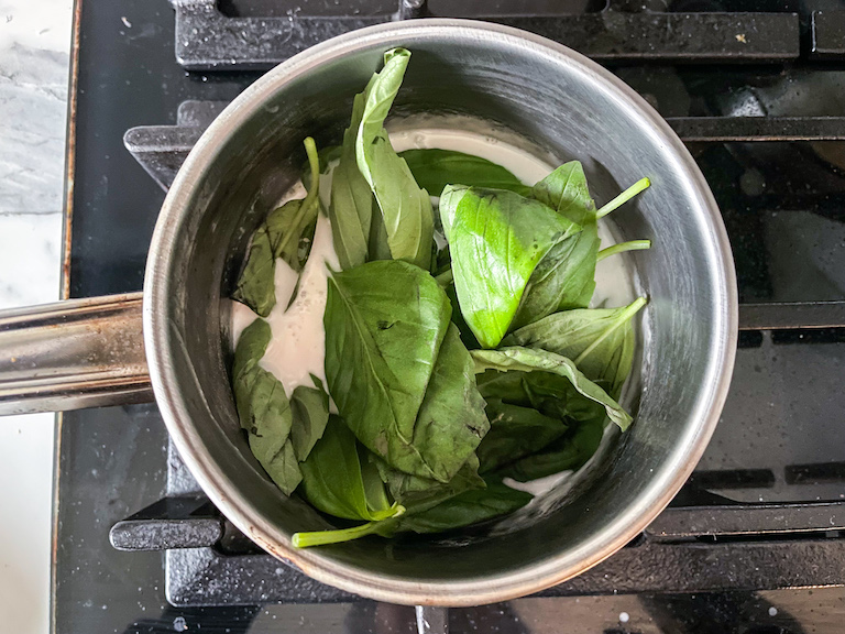 Basil leaves and coconut cream in a saucepan