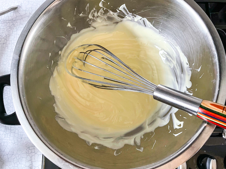 Melted white chocolate in a bowl with a whisk