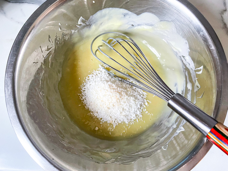 Whisking coconut into a bowl of melted white chocolate