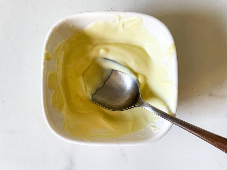 Bowl of melted white chocolate with a spoon